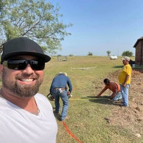 Brandon on site while the crew stakes out a pool shape across a large yard