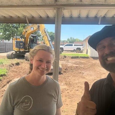 Brandon with a homeowner under a covered patio as their pool is dug out